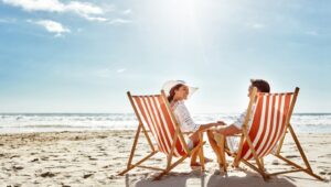couple sitting in beach chairs on sunny beach